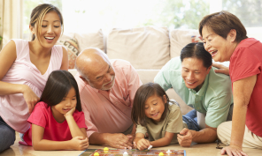 Three generations of an Asian family playing a board game together.