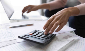 A person's hands resting on a calculator and documents.