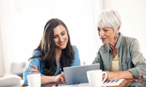 A young woman helping an older woman on her laptop.