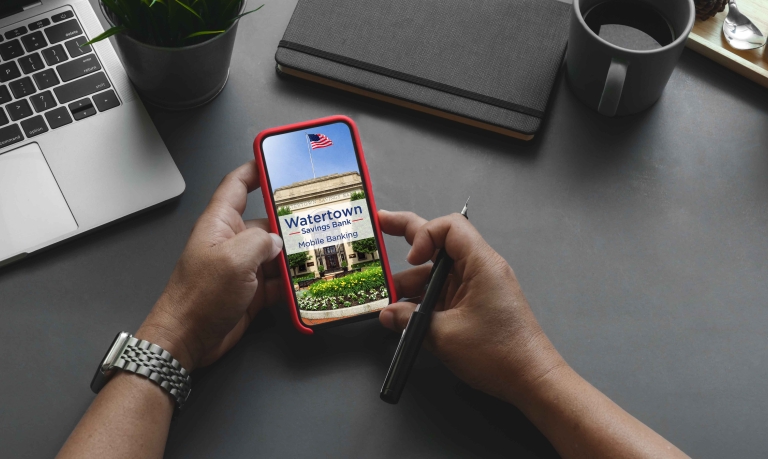 Person checking their WSB Mobile Banking app with a laptop nearby.