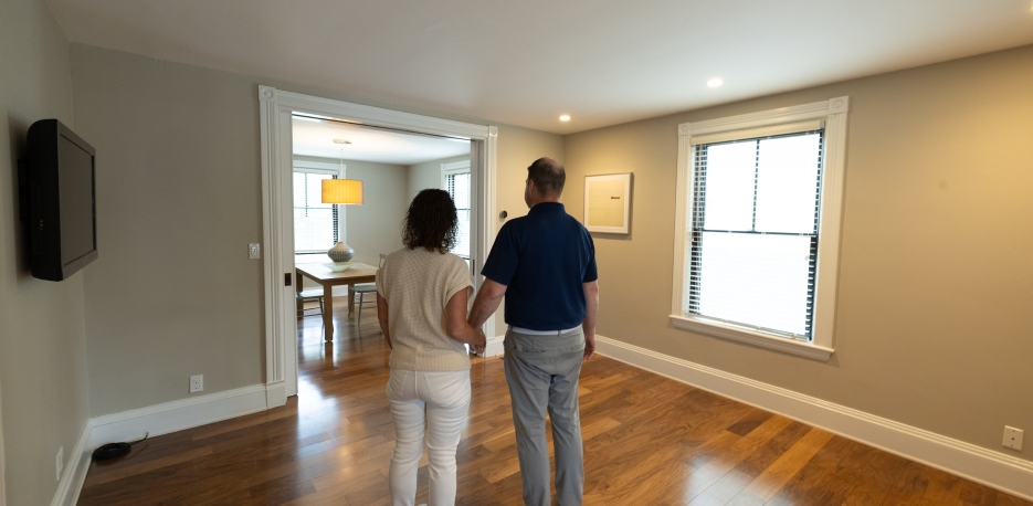A couple walking through a new, empty house on the market for sale.