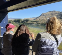 Three women looking out the window from a train.