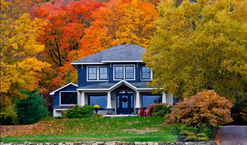 Colonial house surrounded by fall foliage and colorful trees