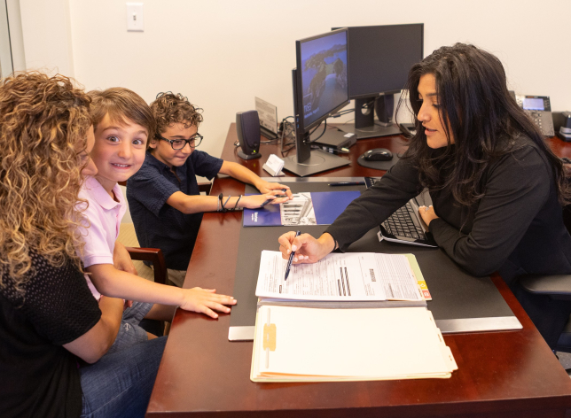 A WSB loan officer review documents with a customer while her son smiles to the camera.
