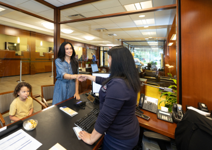 A WSB personal banker shaking hands with a customer whose son is sitting on a chair.