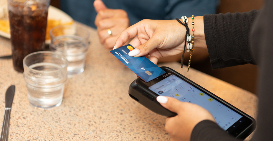 Waitress tapping a WSB debit card to make a contactless payment.