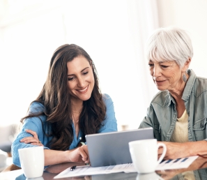 Young woman helping an older woman on the laptop.