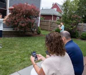 Parents checking their WSB accounts on their phone while their boys are throwing around a ball.