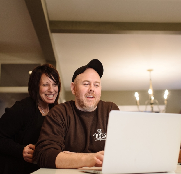Couple smiling and looking at a laptop.