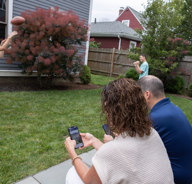 Parents checking their WSB accounts on their phone while their boys are throwing around a ball.